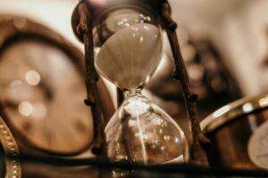 Sanduhr vor unscharfer Uhr im Hintergrund – Symbolbild für Verjährung und Beginn der Festsetzungsfrist im Schenkungsteuerrecht