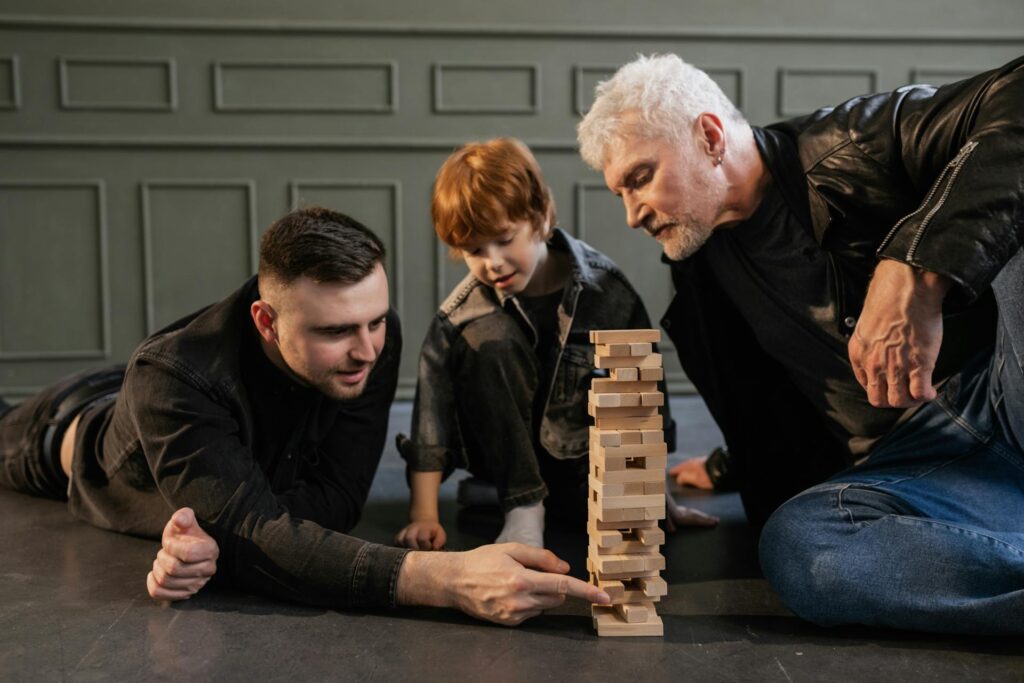 Drei Generationen spielen gemeinsam Jenga – Symbolbild für sorgfältige Planung der Unternehmensnachfolge und Betriebsübertragung zu Lebzeiten