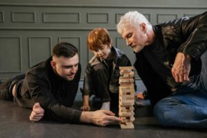 Drei Generationen spielen gemeinsam Jenga – Symbolbild für sorgfältige Planung der Unternehmensnachfolge und Betriebsübertragung zu Lebzeiten