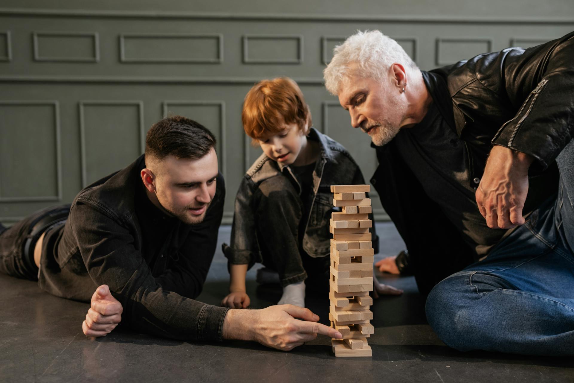 Drei Generationen spielen gemeinsam Jenga – Symbolbild für sorgfältige Planung der Unternehmensnachfolge und Betriebsübertragung zu Lebzeiten
